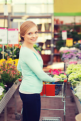 Image showing happy woman with shopping trollye buying flowers