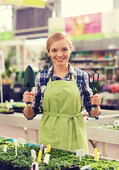 Image showing happy woman with gardening tools in greenhouse