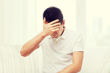 Image showing unhappy man suffering from head ache at home