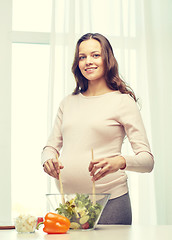 Image showing happy pregnant woman preparing food at home