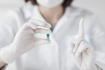 Image showing close up of scientist holding pill in lab