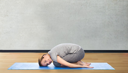 Image showing happy woman making yoga in child pose on mat