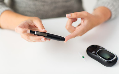 Image showing close up of woman making blood test by glucometer