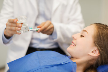 Image showing happy dentist showing jaw layout to patient girl