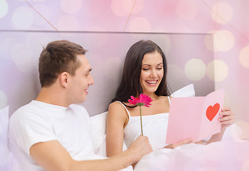 Image showing happy couple in bed with postcard and flower