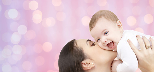 Image showing happy mother kissing her baby over pink lights