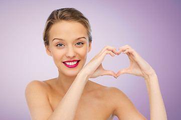 Image showing smiling young woman showing heart shape hand sign