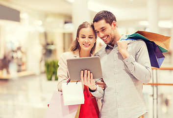 Image showing couple with tablet pc and shopping bags in mall