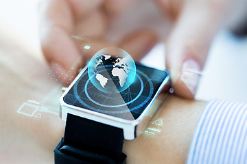 Image showing close up of hand with globe hologram on smartwatch