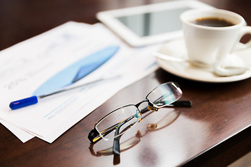 Image showing close up of glasses, tablet pc, charts and coffee