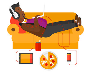 Image showing Man with gadgets lying on sofa.