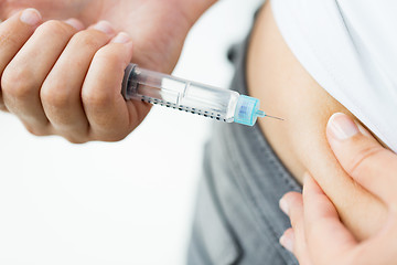 Image showing close up of hands making injection by insulin pen