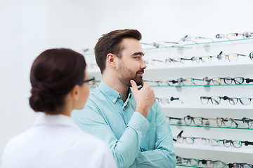 Image showing optician showing glasses to man at optics store