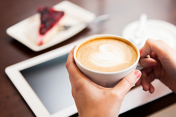 Image showing close up of hands with coffee, tablet pc and cake