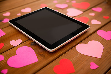 Image showing close up of tablet pc and hearts on wood
