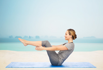 Image showing woman making yoga in half-boat pose on mat