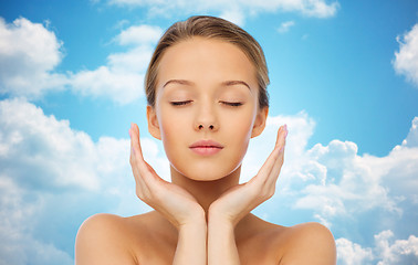 Image showing young woman face and hands over blue sky