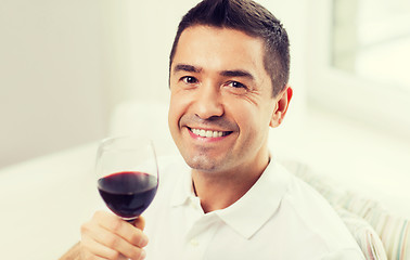 Image showing happy man drinking red wine from glass at home