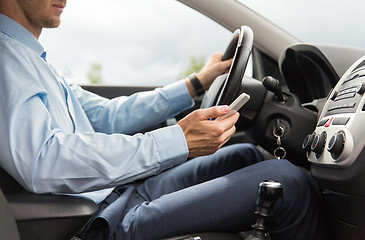 Image showing close up of man with smartphone driving car