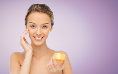 Image showing happy young woman applying cream to her face