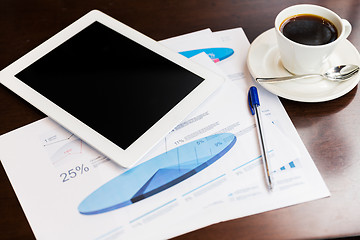 Image showing close up of tablet pc, charts and coffee on table