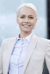 Image showing young smiling businesswoman over office building