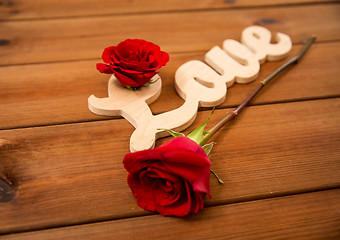 Image showing close up of word love cutout with red rose on wood