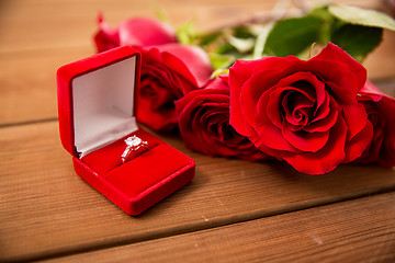 Image showing close up of diamond engagement ring and red roses