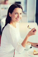 Image showing smiling young woman with cake and coffee at cafe