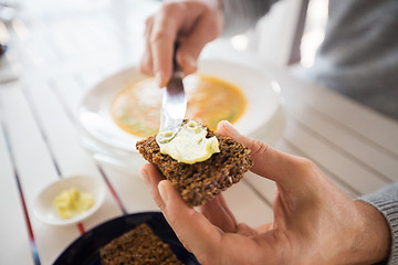 Image showing close up of hands applying butter to bread