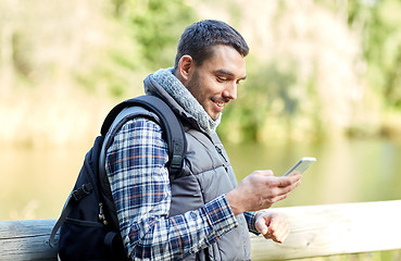 Image showing happy man with backpack and smartphone outdoors