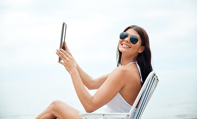 Image showing smiling woman with tablet pc sunbathing on beach