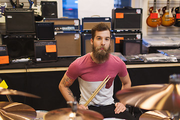 Image showing male musician with cymbals at music store