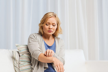 Image showing unhappy woman suffering from hand inch at home