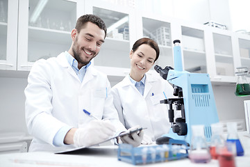 Image showing scientists with clipboard and microscope in lab