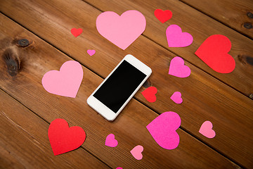 Image showing close up of smartphone and hearts on wood