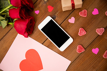 Image showing close up of smartphone, gift, red roses and hearts