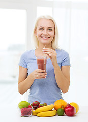 Image showing smiling woman drinking fruit shake at home