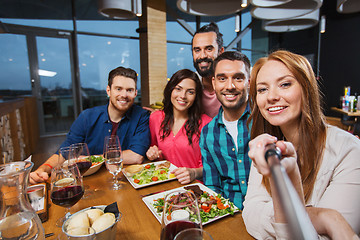 Image showing friends picturing by selfie stick at restaurant