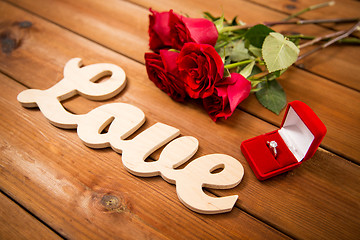 Image showing close up of diamond ring, red roses and word love