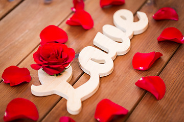 Image showing close up of word love cutout with red rose on wood