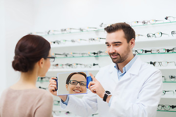 Image showing woman in glasses looking to mirror at optics store