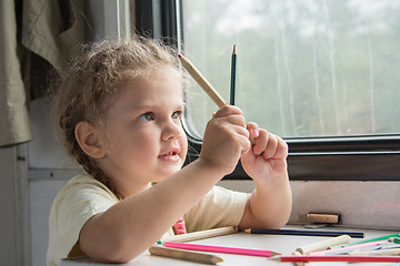 Image showing Girl looks funny on pencils at the table in the second-class train carriage