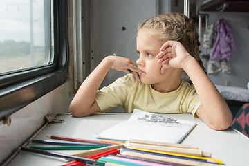 Image showing The girl looked out the window thinking drawing pencils in a train