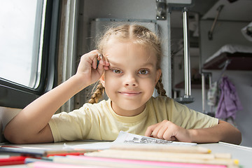 Image showing Girl happily looks into the frame, drawing pencils in a train