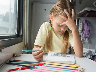 Image showing Six year old girl thoughtfully draws pencils in second-class train carriage