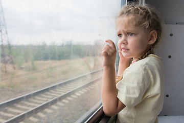 Image showing Four-year girl with astonishment looks in the window of a train
