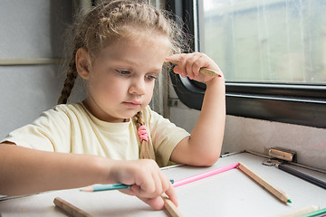 Image showing Four-year girl playing with pencils reserved seats at a table in a train