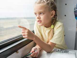 Image showing Girl shows a finger in the second-class car of a train window