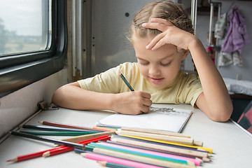 Image showing Six-year girl joyfully draws pencils in second-class train carriage